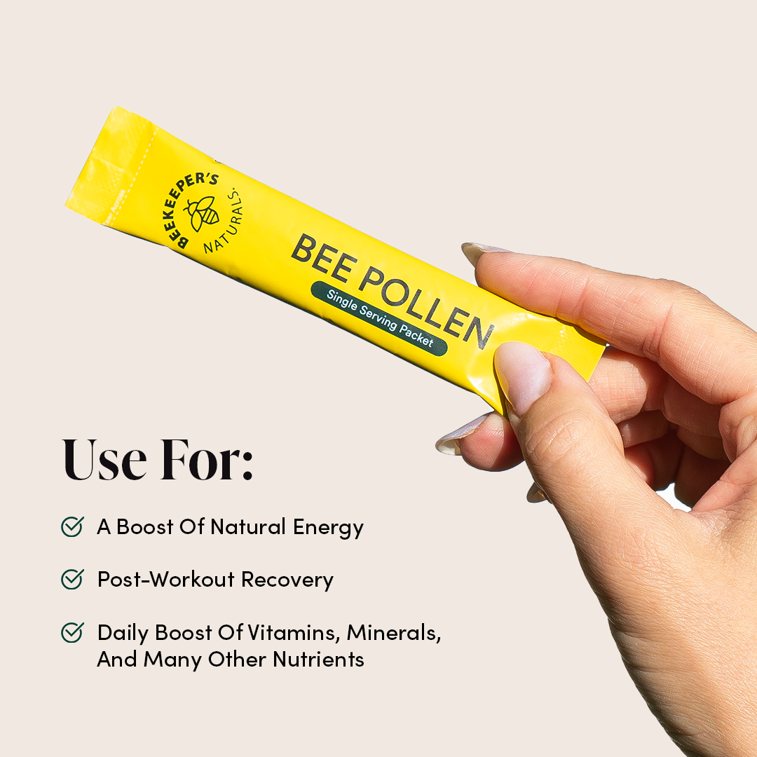 Hand holding a Bee Pollen packet from Beekeeper's Naturals. Text indicates benefits for energy, recovery, and daily vitamins.
