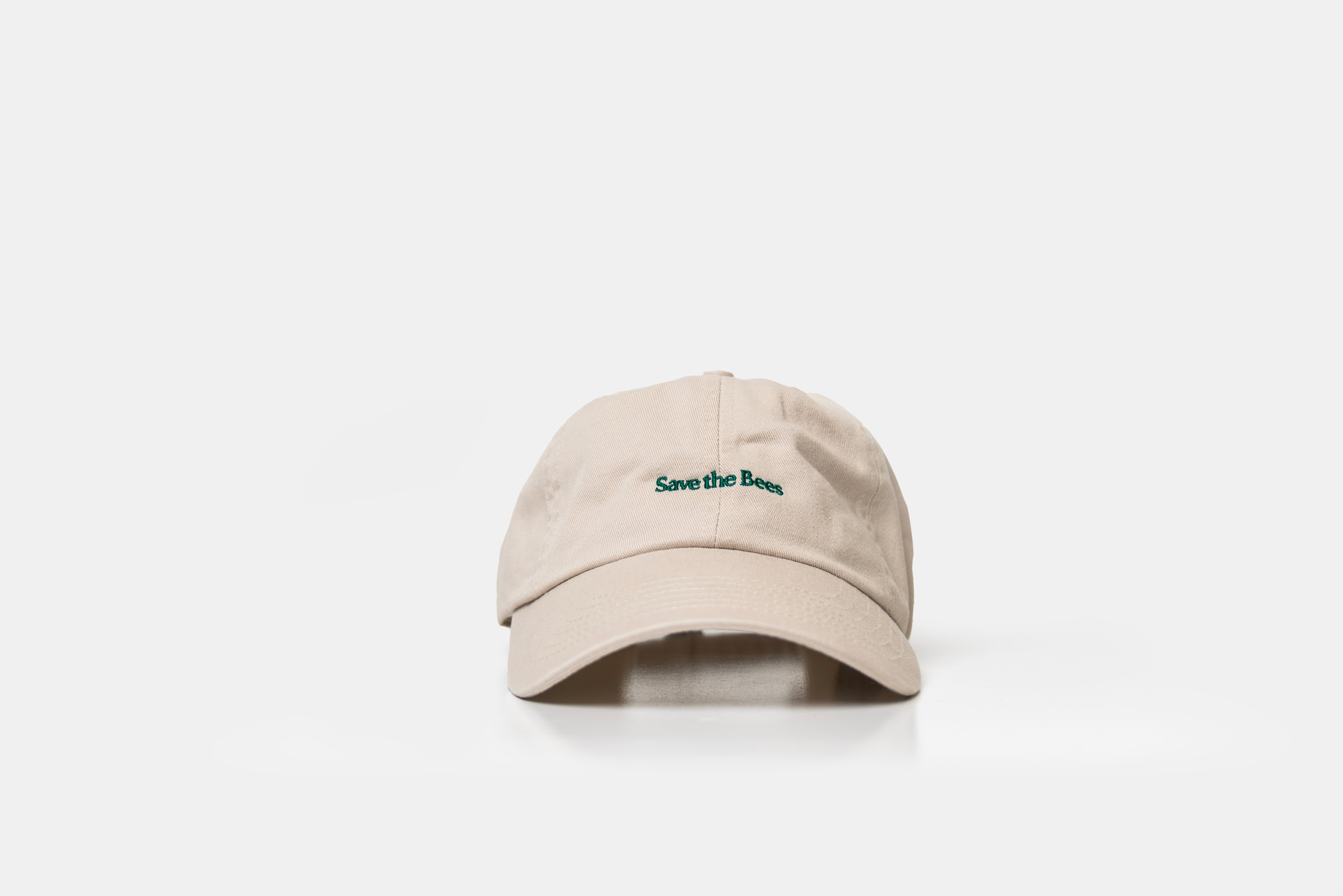 A beige baseball cap with 'Save the Bees' embroidered in green on the front, set against a plain white background.