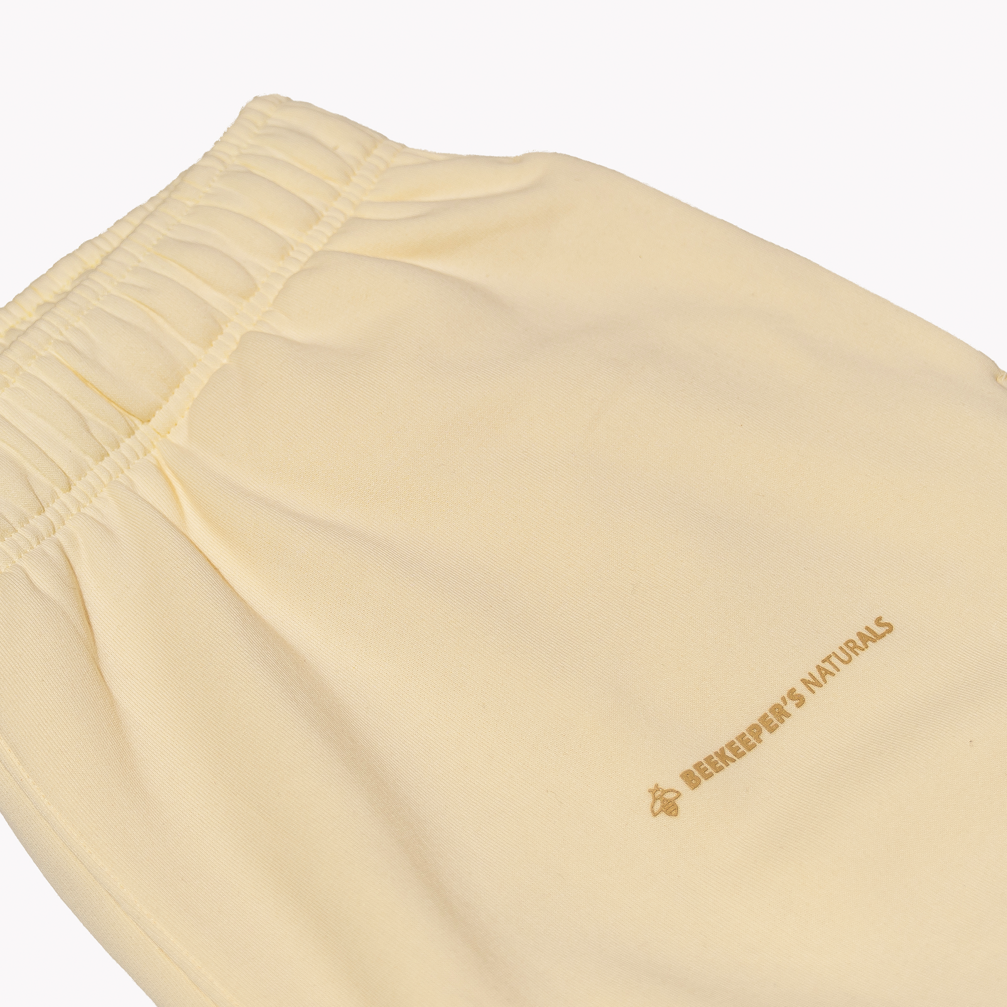Cream shorts with a brand logo on a white background
