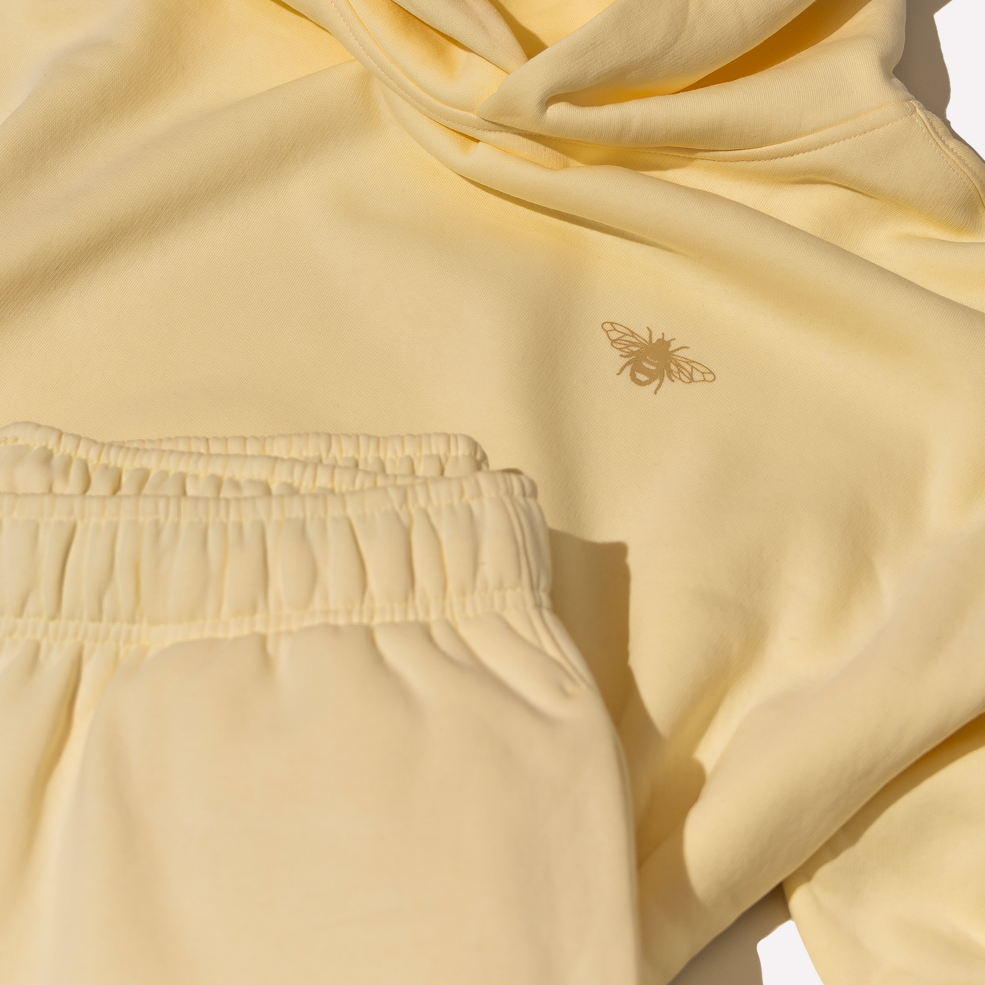 Cream hoodie with a bee emblem on a light background