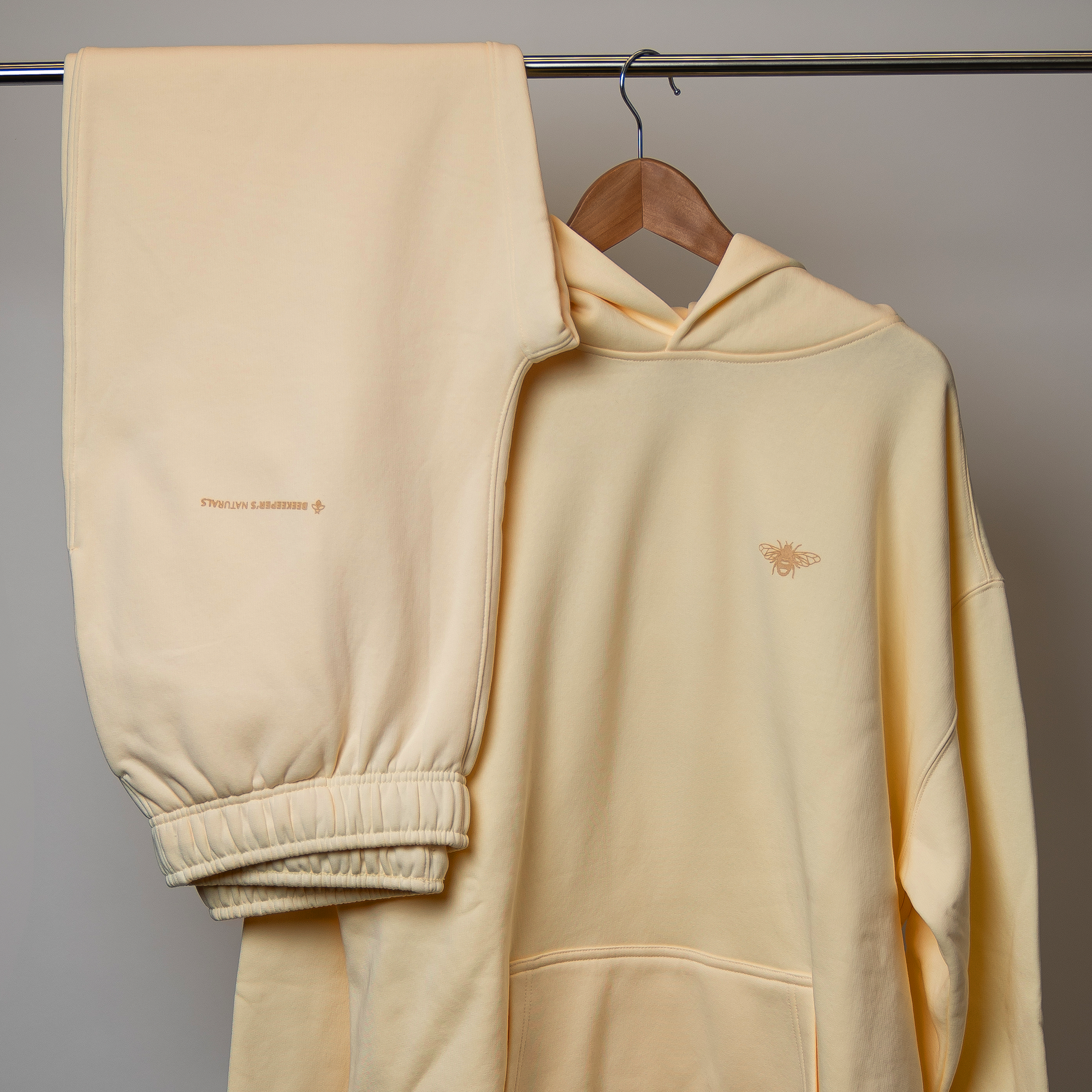 Cream hoodie and pants set with brand logo on a gray background