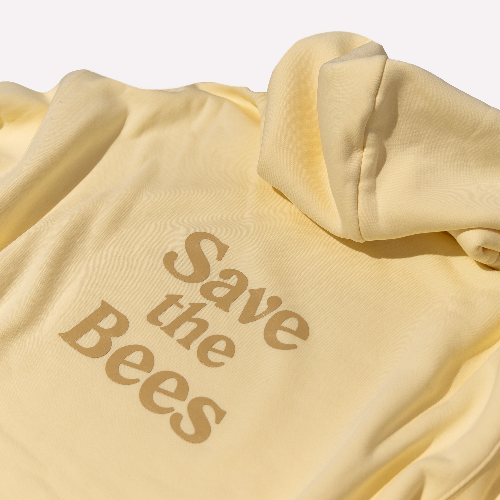 Cream hoodie with 'Save the Bees' text on a beige background
