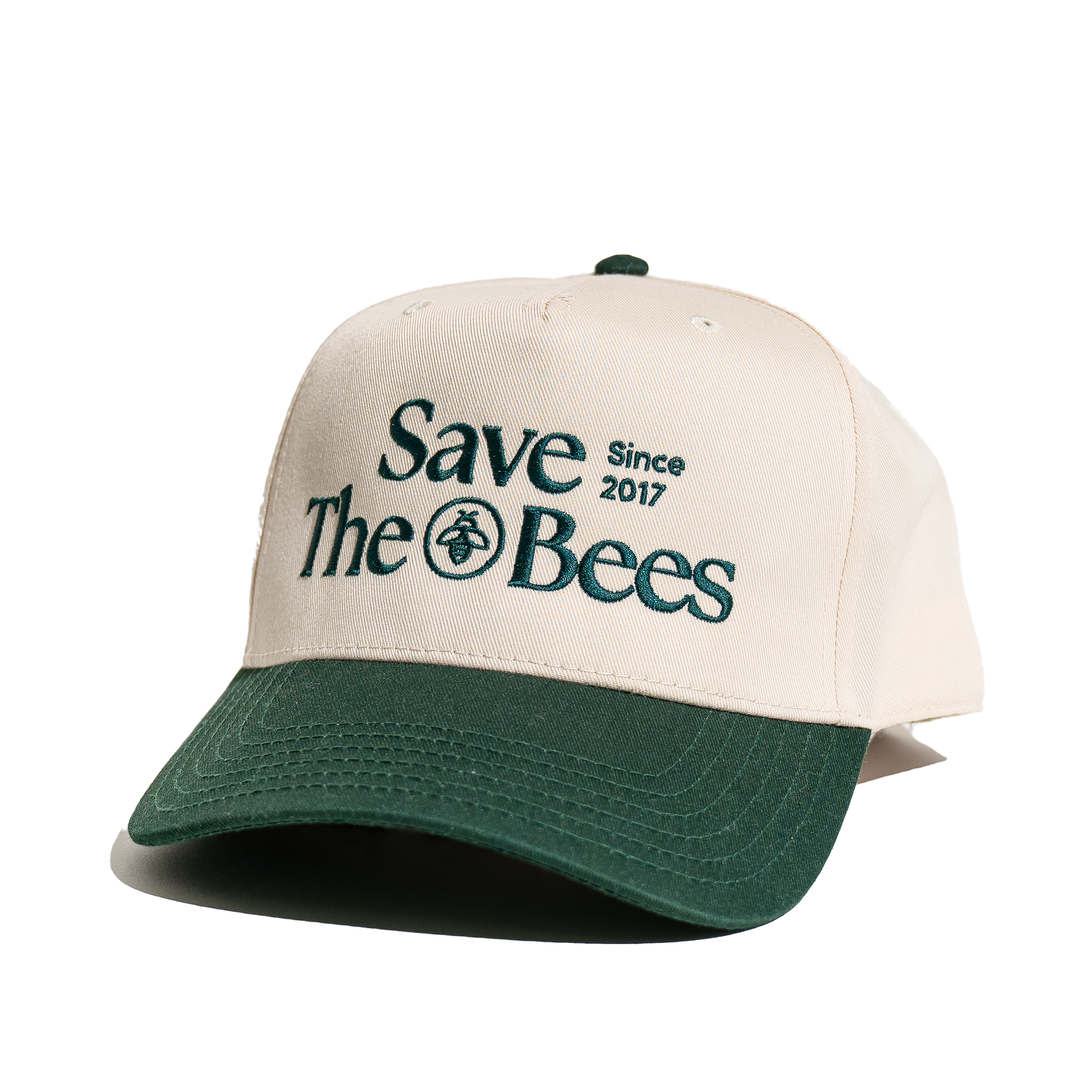 Save The Bees trucker hat detail. Embroidered text 'Save The Bees Since 2017' with bee graphic on a two-tone hat.