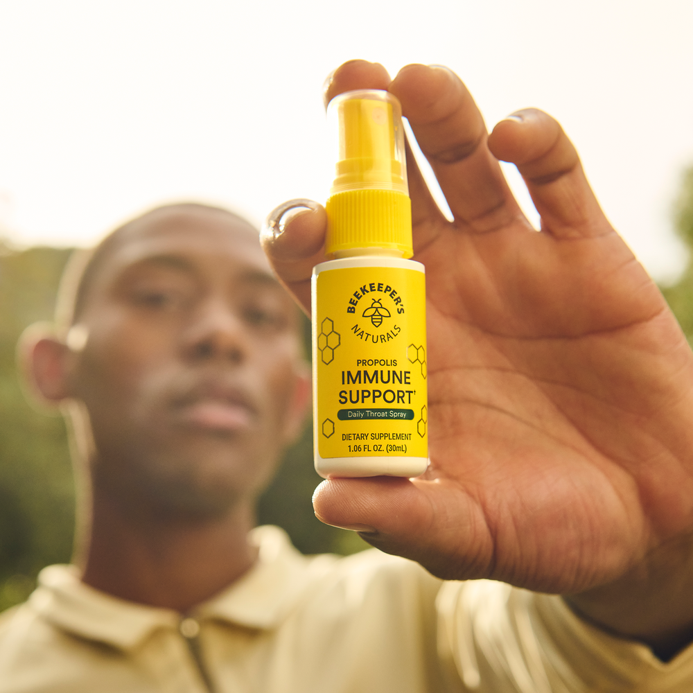 A hand holds Beekeepers Naturals Propolis Throat Spray. Immune support and natural wellness product.