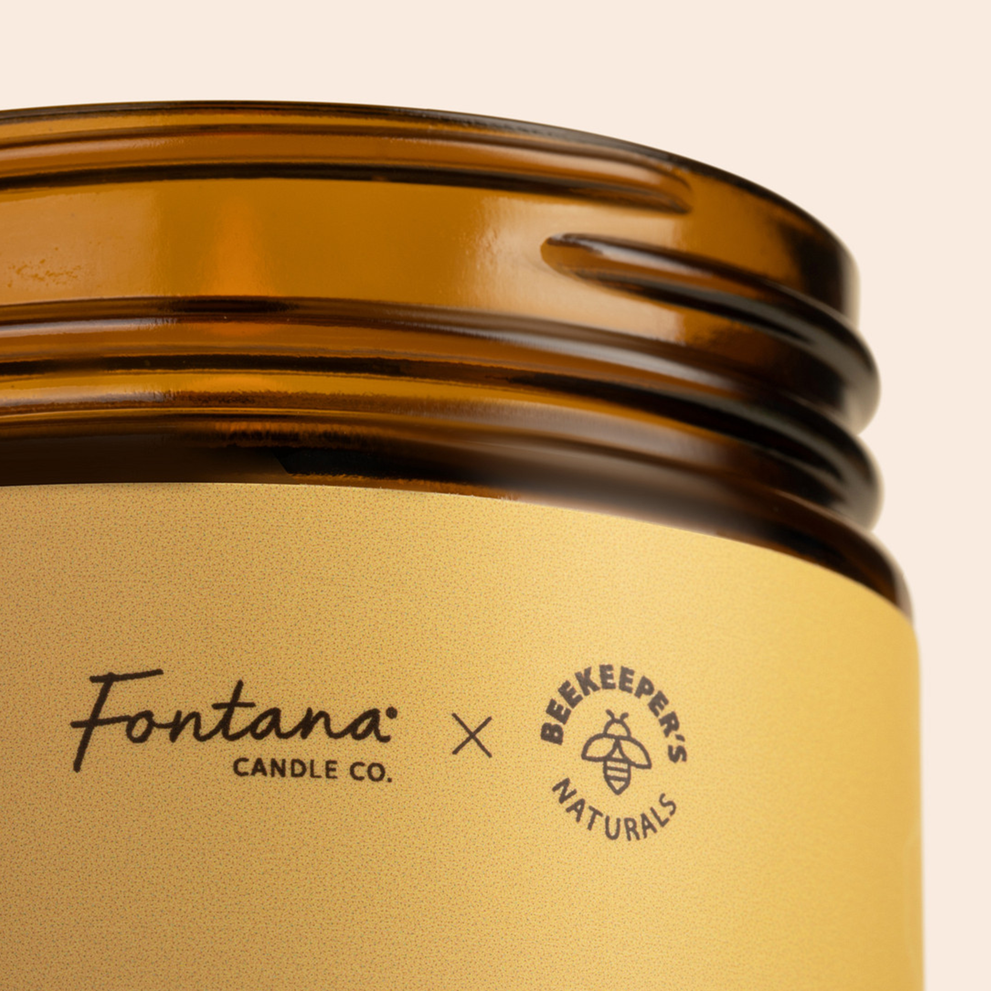 Close-up of Wildflower Honey Fontana Candle jar showing Fontana Candle Co. and Beekeeper's Naturals logos on a gold label and amber glass