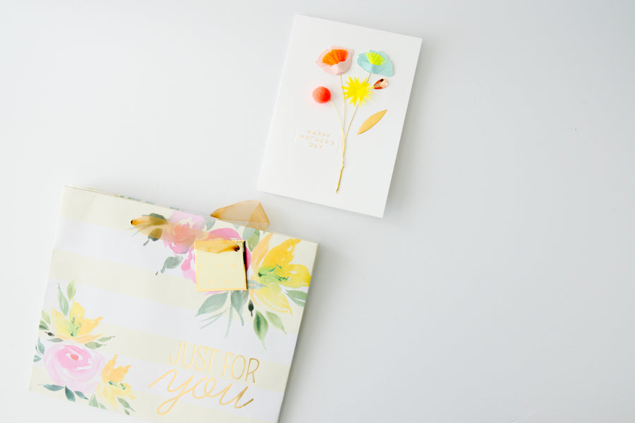 Floral gift bag reading Just for you beside a handmade floral Mother's Day card on a white background