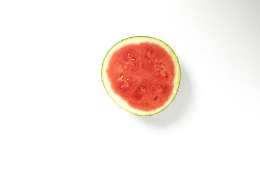 Overhead view of a halved watermelon showing red flesh and seeds on a white background