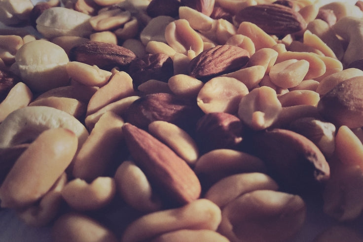 Close-up of mixed shelled nuts showcasing almonds and peanuts with varied textures and a blurred background