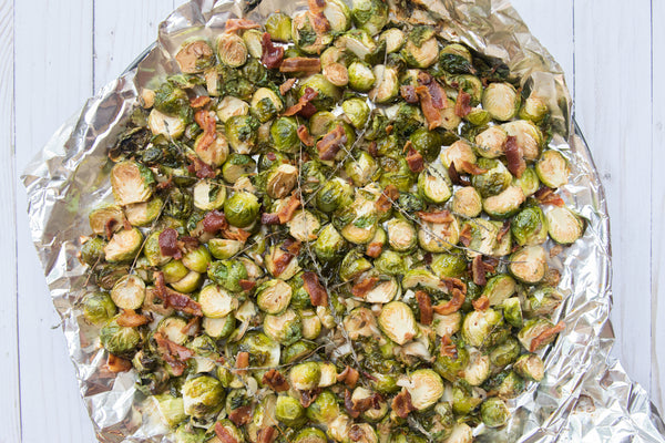 Overhead of roasted Brussels sprouts with crispy bacon on crumpled aluminum foil