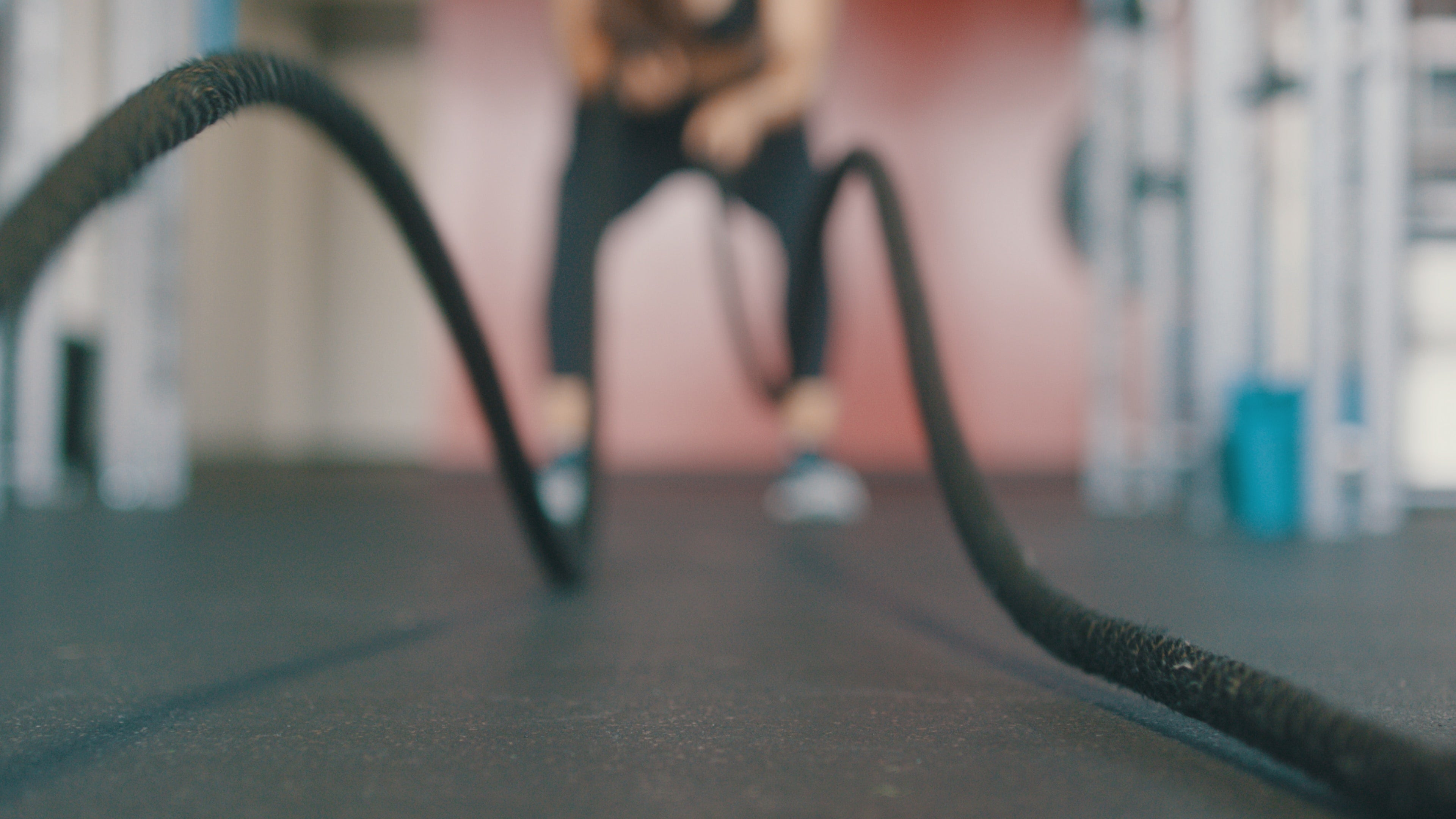 Low-angle view of a person using battle ropes in a gym, ropes in focus and person blurred in background