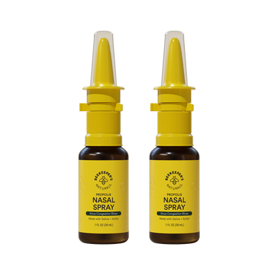 Two bottles of nasal spray with yellow labels on a white background