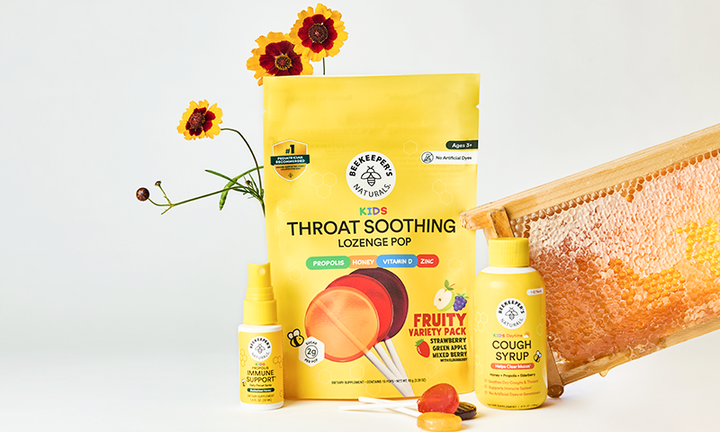 Kids cough syrup, throat soothing lozenges, and propolis immune support displayed with honeycomb and flowers