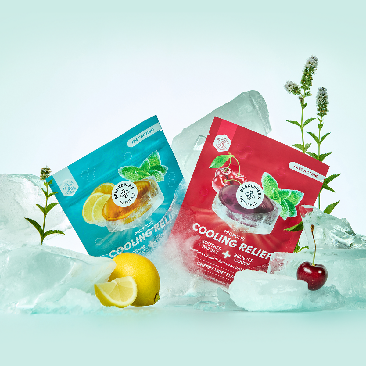 Two cooling relief packets, one blue with lemon imagery and one red with cherry imagery, arranged among ice cubes, a lemon slice, and a cherry on a pale mint-green background.