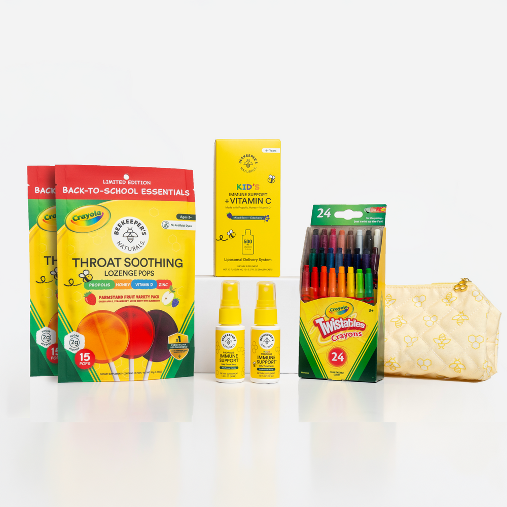 A back-to-school essentials gift set featuring two boxes of Crayola Throat Soothing Lozenges, a box of Crayola Kids Vitamin C tablets, a pack of 24 Twisted Brands markers, two small bottles of hand sanitizer, and a quilted cream zip pouch on a white background.