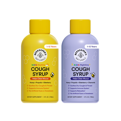 Two bottles of Beekeeper's Naturals cough syrup, one yellow and one purple, on a white background.