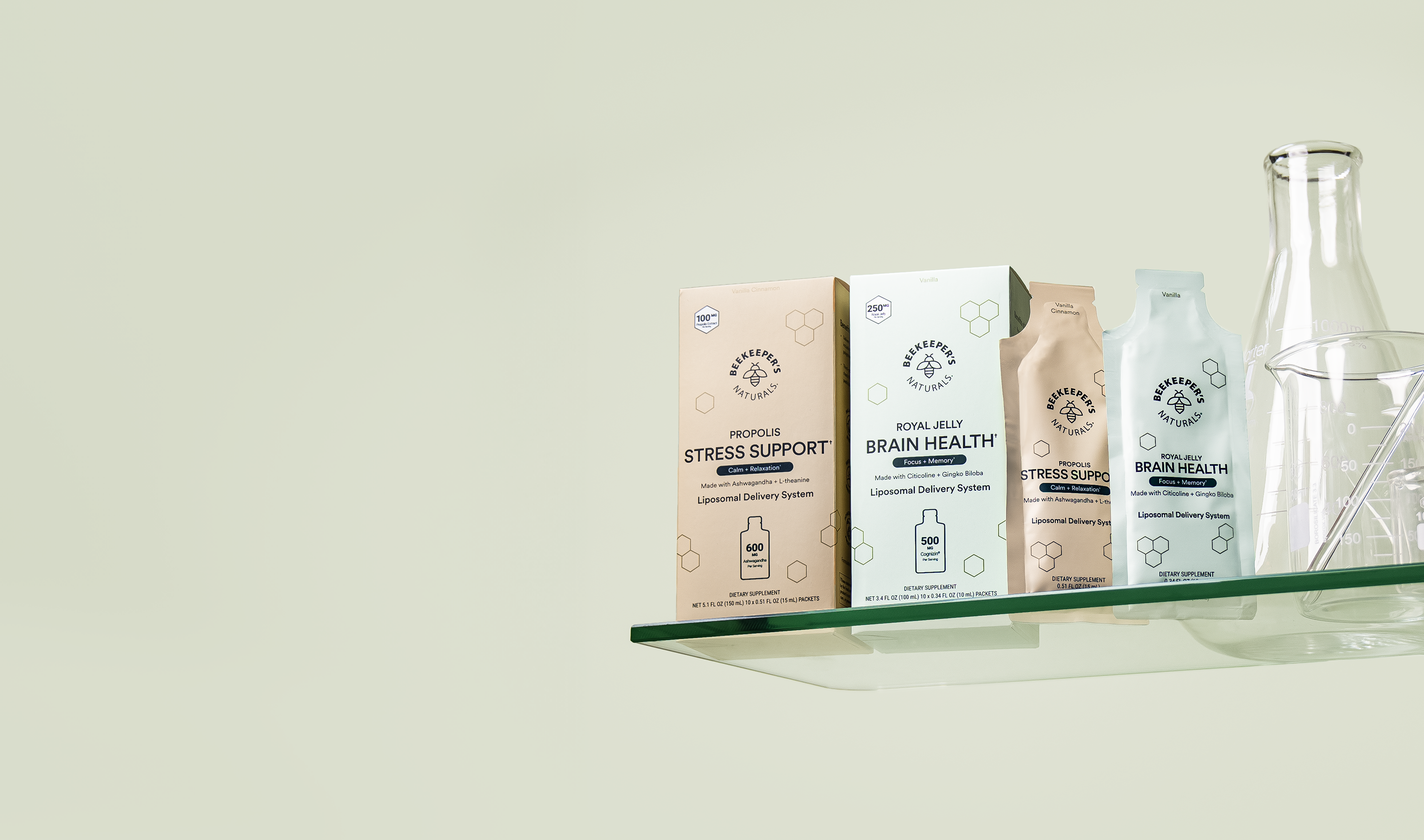 Four wellness product packages for stress support and brain health displayed on a glass shelf next to a clear glass carafe, set against a light green background.