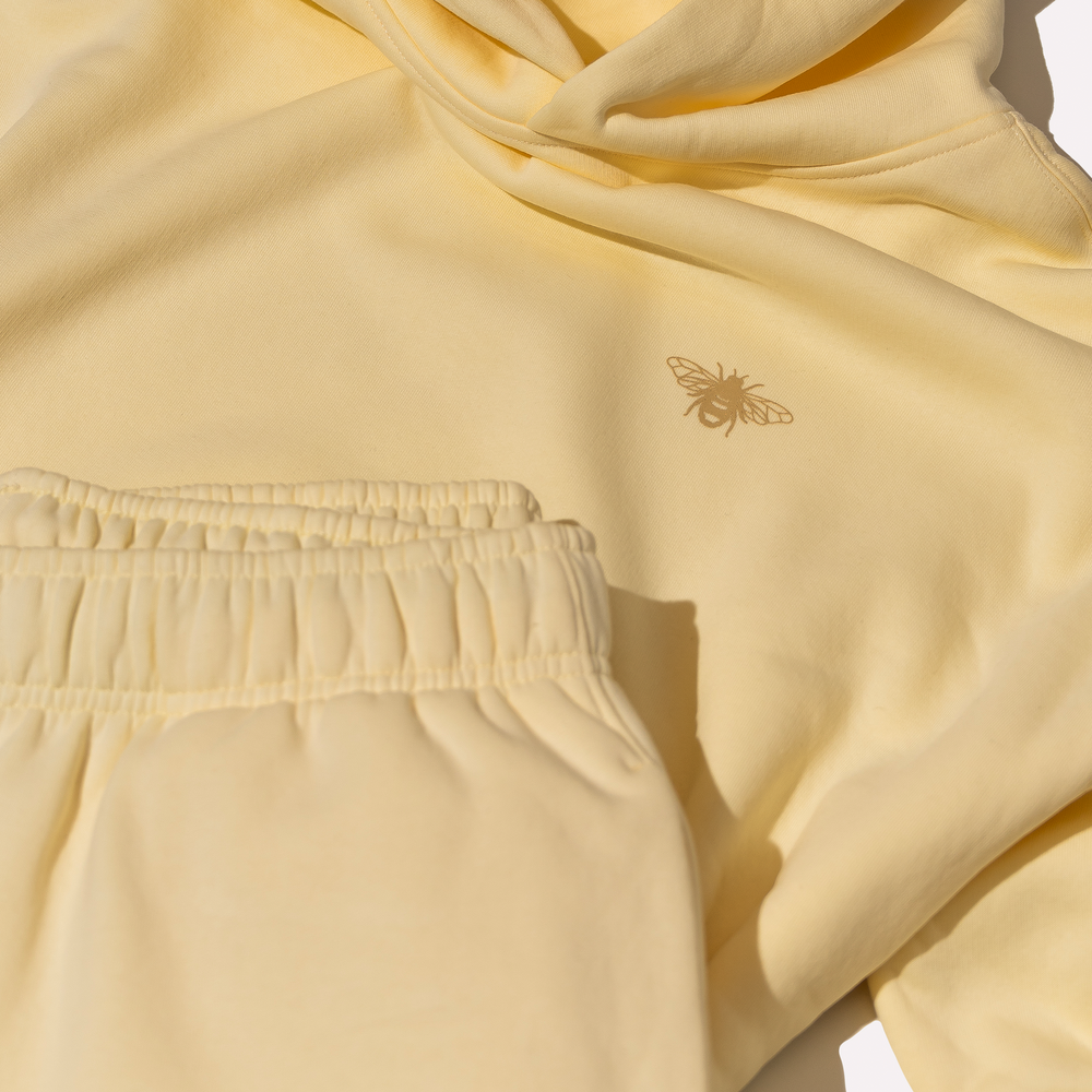 Cream hoodie with a bee emblem on a light background