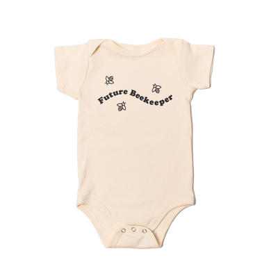 Beige baby onesie with 'Future Beekeeper' text and bee illustrations on a white background