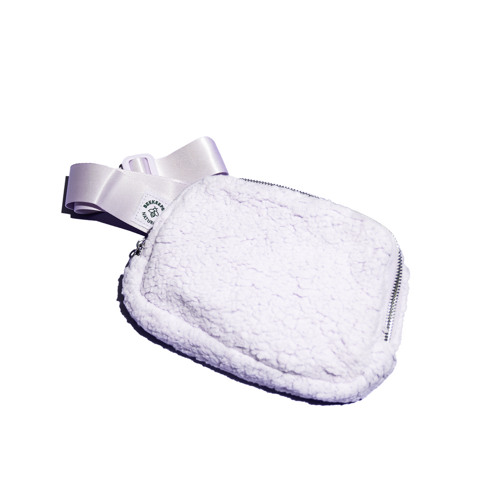 Purple BKN Belt Bag. Fluffy sherpa material with logo on the lavender strap, detail showcasing the bag's texture and design.