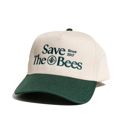Save The Bees trucker hat detail. Embroidered text 'Save The Bees Since 2017' with bee graphic on a two-tone hat.