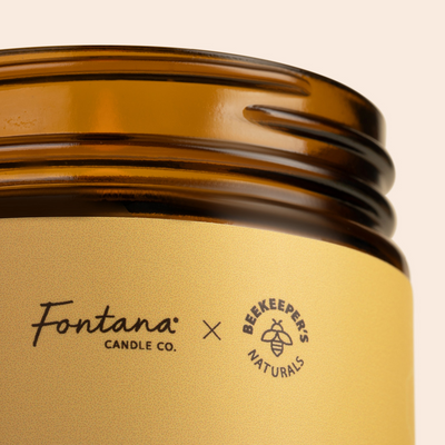 Close-up of Wildflower Honey Fontana Candle jar showing Fontana Candle Co. and Beekeeper's Naturals logos on a gold label and amber glass