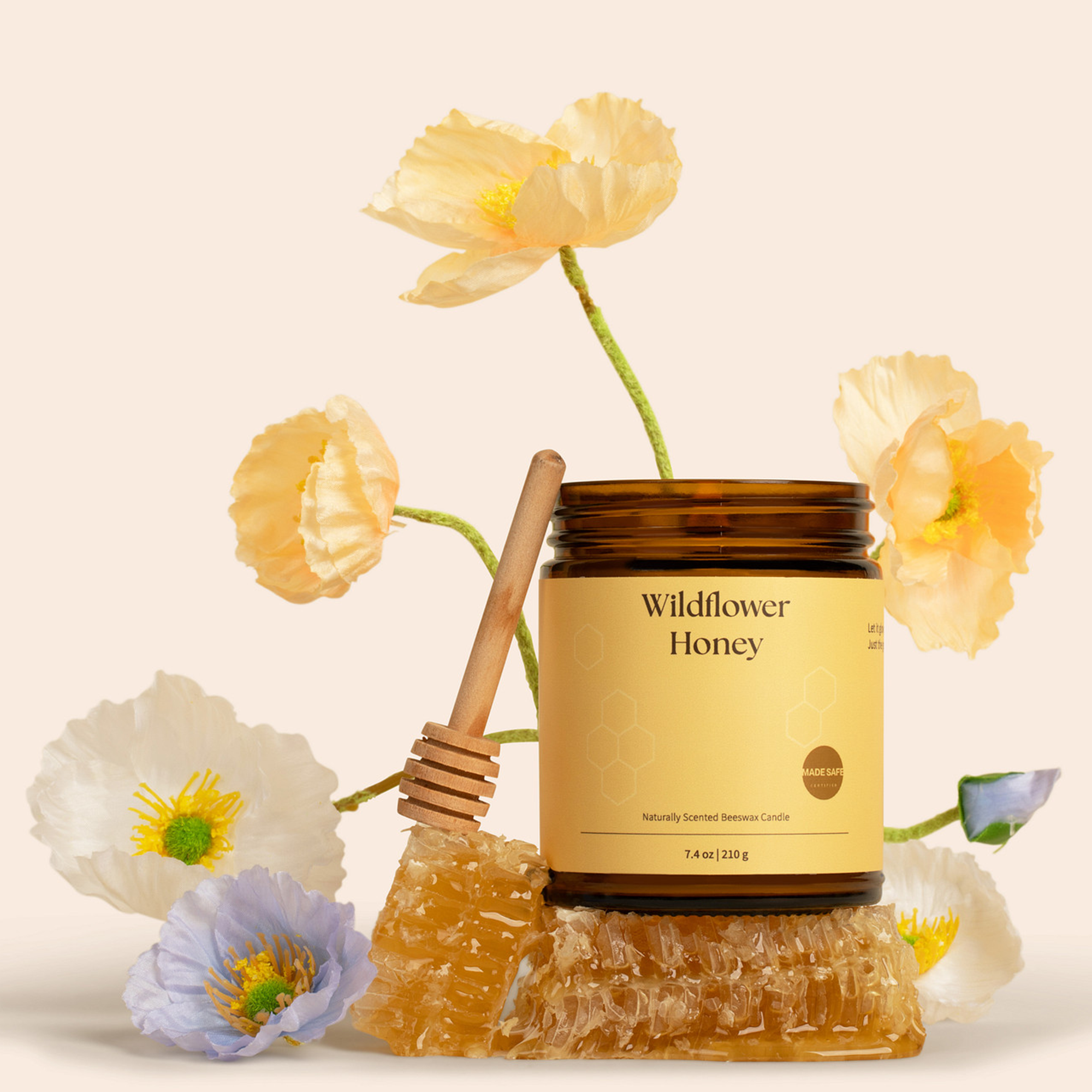 Front Wildflower Honey candle in amber jar showing label Wildflower Honey, honeycomb, dipper, and flowers on beige backdrop