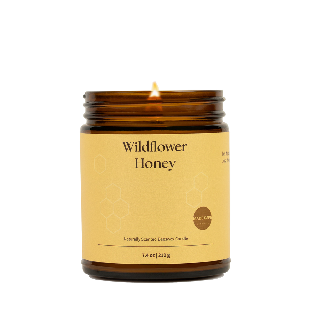 Candle in an amber jar labeled 'Wildflower Honey' on a white background