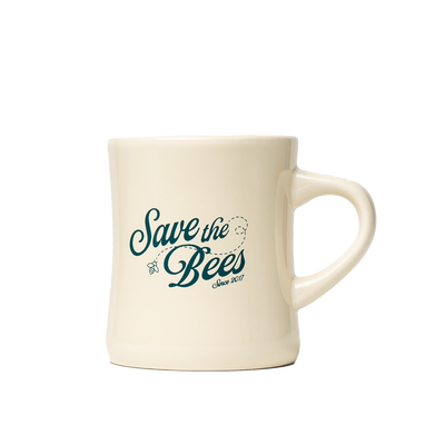 Three-quarter view of cream diner mug showcasing green Save the Bees script on transparent background